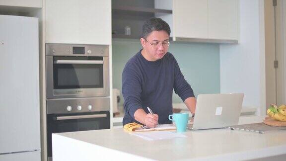 亚洲华人男性在厨房柜台使用笔记本电脑进行视频通话