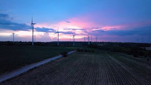 日落时被风力涡轮机包围的绿色田野鸟瞰图