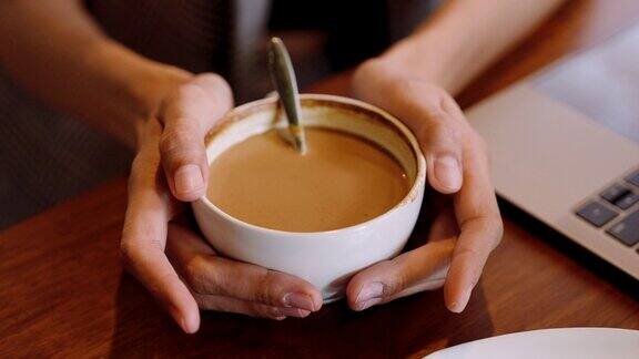 亚洲女性双手捧着咖啡杯的手指特写有满满一杯咖啡准备吃那个女人摆动着手指表达紧张的想法