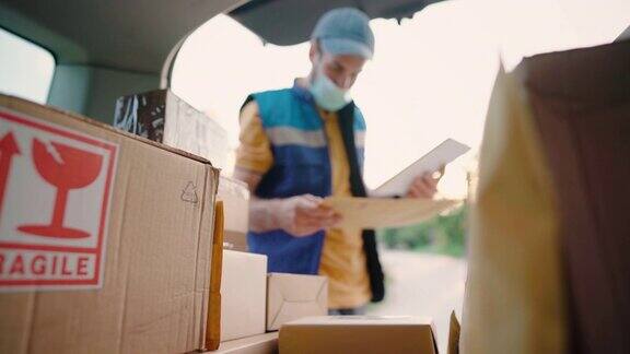 年轻的送货员正在检查汽车后备箱里的送货地址