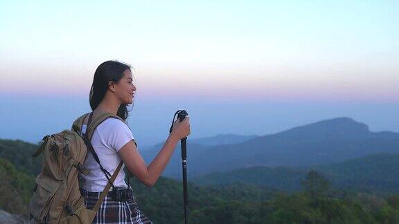 一位年轻的女游客正在山顶徒步旅行观赏美丽的风景