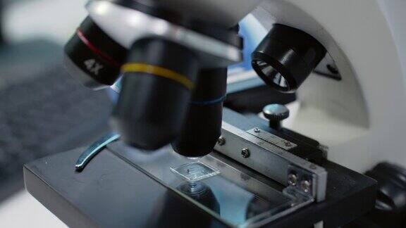 近距离的实验室显微镜与托盘的流体样品研究