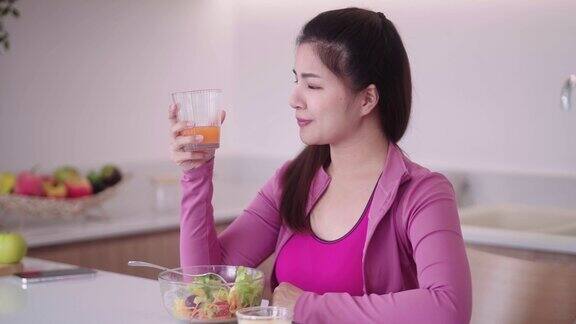 健康运动的亚洲年轻女性穿着运动服在家里的厨房里喝果汁运动后的健康饮食健康排毒和减肥