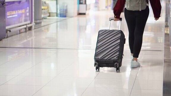 旅行家女士走过机场航站楼与手提箱在机场旅游概念