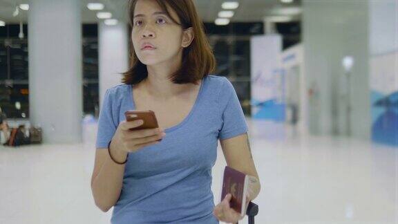 年轻女性站在机场用智能手机查看打架情况