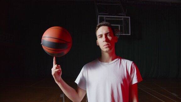 特写白种人年轻篮球运动员肖像红光光束黑黑篮背景花样与球