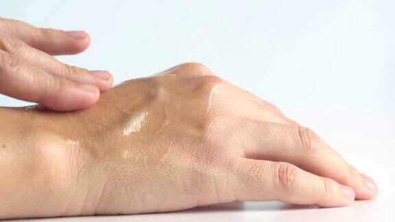 女性双手护理近距离拍摄的妇女将面霜涂在手皮肤上含透明质酸的精华油女性用手涂抹护肤化妆品保湿凝胶