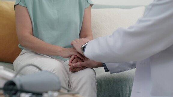 亚洲男性医生触摸老年病人的手以一种令人放心的方式