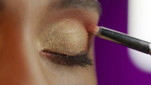 一个女孩的眼睛特写化妆师用化妆刷涂抹眼影