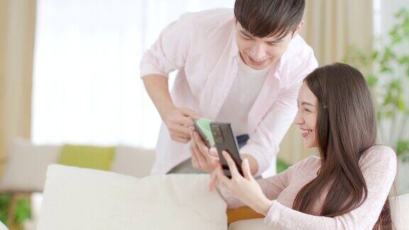 幸福的年轻夫妇在家里的客厅里看手机