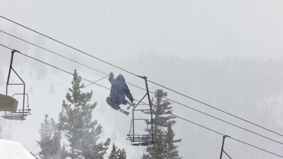 在科罗拉多州博尔德附近的埃尔多拉滑雪度假村在一个阴天多雪的冬日里完成一个跳跃与森林和滑雪缆车的“左540双抓”技巧