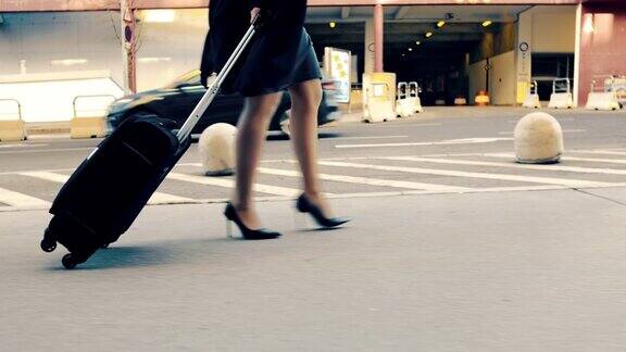 穿着高跟鞋提着行李箱走在机场人行道上的MS女商人