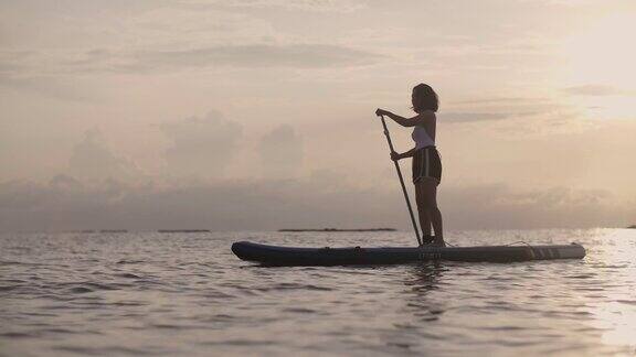 一个年轻的女人在夕阳下划着小船