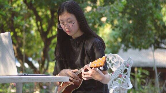 亚洲少女在后院学习尤克里里琴