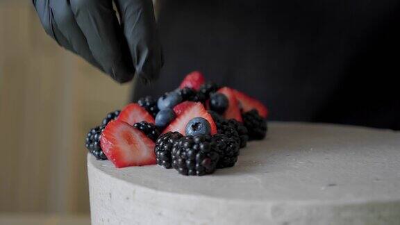 年轻女子烹饪和装饰蛋糕用奶油装饰红草莓关闭V2