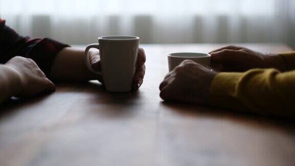 女人和男人在桌子上拿着咖啡杯的特写