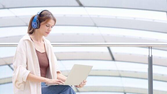 在机场候机楼旅行时女商人坐在行李上用笔记本电脑进行在线会议