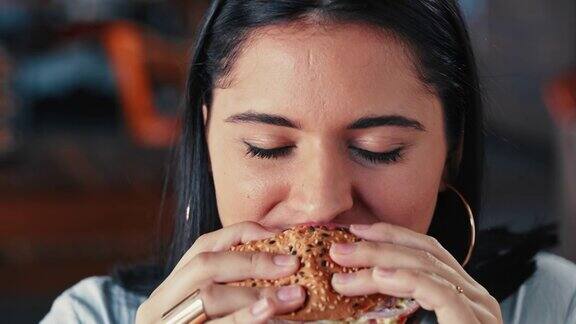 一个年轻女子在餐厅里吃汉堡的4k视频