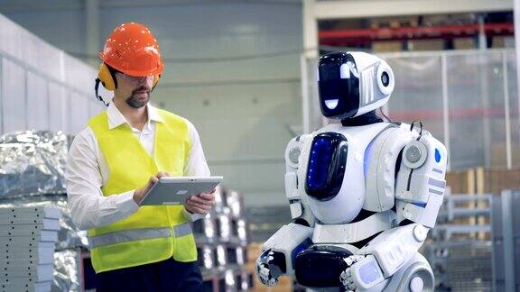 工厂员工正在用手势与一个人形机器人交流