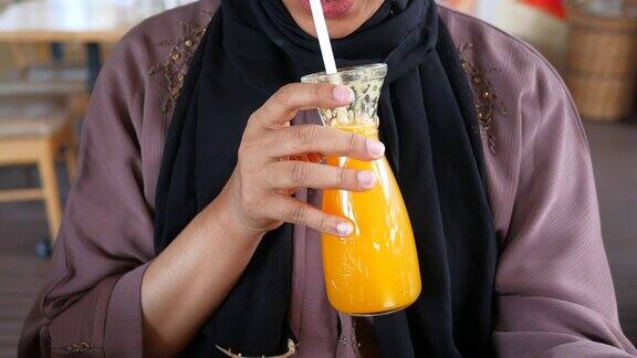 女人坐在咖啡馆里喝橙汁