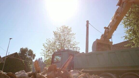 挖掘机在阳光下往卡车里装建筑碎片