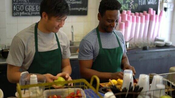 黑人和亚洲人在果汁吧合作销售一个选水果另一个切然后放进搅拌机