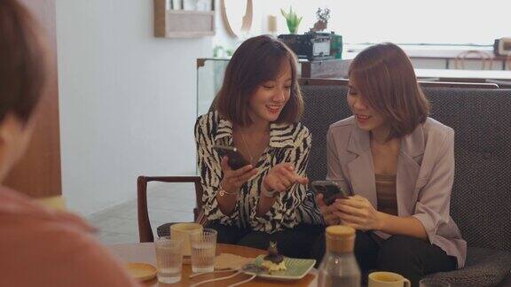 亚洲中国女性使用智能手机支付享受咖啡休息在咖啡馆社交聚会聊天
