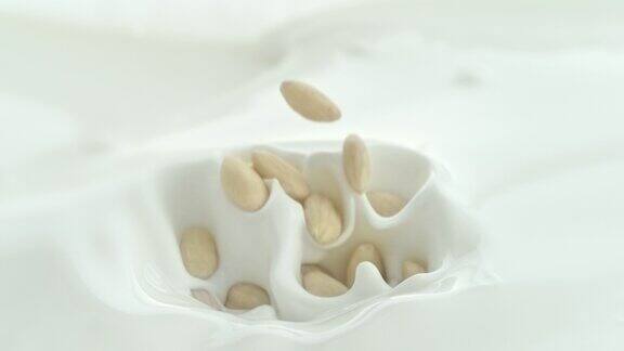 杏仁落入奶油牛奶中在微距和慢镜头中产生漩涡飞溅