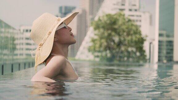 亚洲女子在酒店游泳池享受新鲜空气