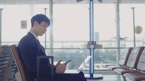 在机场用笔记本电脑工作的亚洲商人