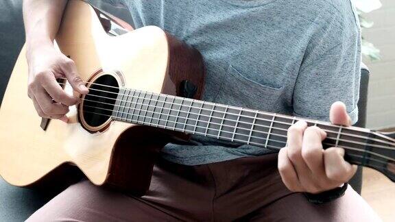 音乐家亚洲男性弹奏原声吉他唱歌学习练习悠闲的时间坐在客厅的沙发上度过活动职业