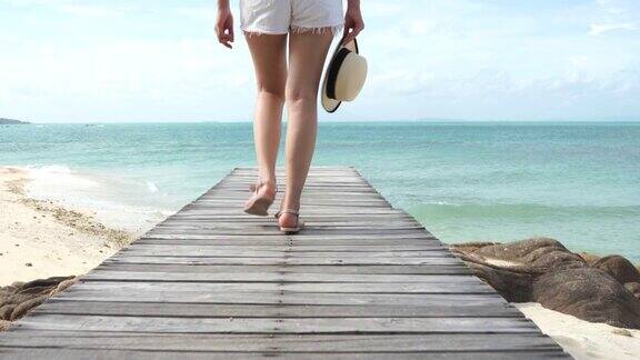 一个女人戴着海帽走在海边的老木桥上