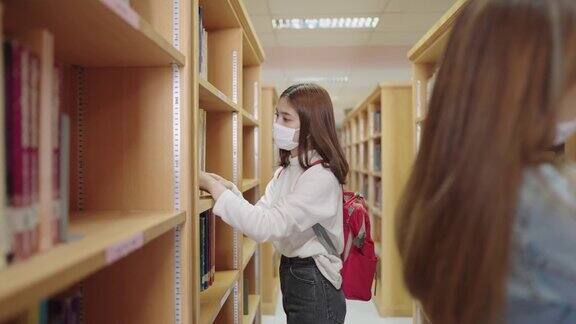 女学生们在大学图书馆的书架上寻找书籍