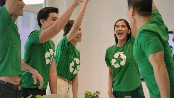 4K志愿者团队开会一群身穿绿色t恤的亚洲青年志愿者双手叠在一起在现代办公室里团结协作