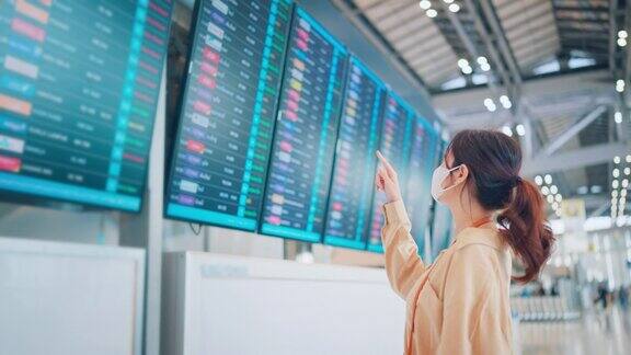 亚洲女旅客在机场候机楼查看航班时刻表旅游旅行概念