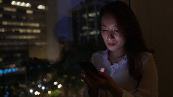 亚洲女商人加班在她的办公室用手机与远程客户和同事沟通