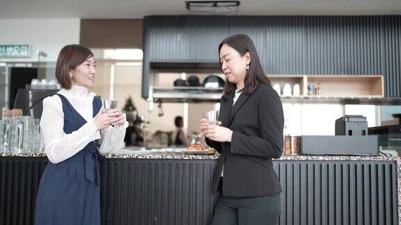 2名亚洲白领女性在办公室自助餐厅喝咖啡休息
