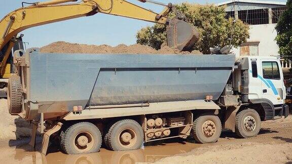 挖掘机将沙子装进自卸卡车(特写)