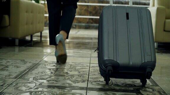 多莉拍摄的女商人的腿走过酒店大厅拉着行李停在前台商务、旅游、人本理念