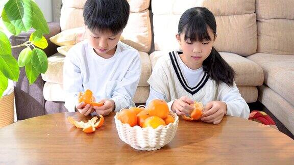 一个亚洲小孩在客厅的小餐桌上吃桔子