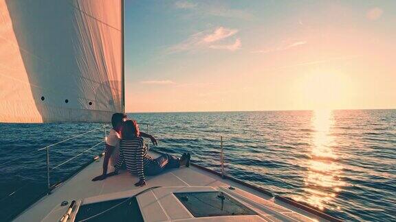 日落时分一对夫妇在一艘帆船的甲板上休息