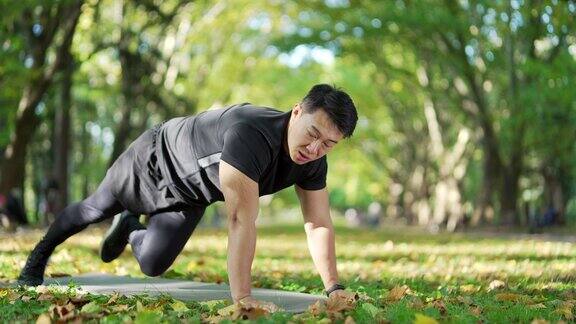 亚洲运动员在城市公园的垫子上做体操一位穿着运动服的英俊男子正在外面忙着锻炼