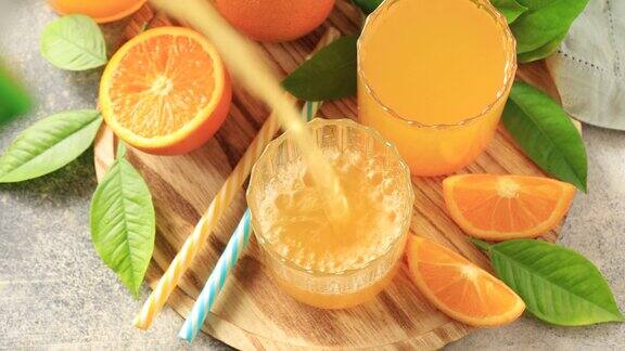 将新鲜的橙汁倒入玻璃杯中石桌上的杯子里放着新鲜的橙汁