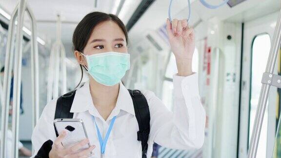 亚洲职业女性乘坐交通轻轨时戴口罩预防新冠病毒在新冠肺炎疫情情况下外出工作时要注意保持社交距离是为了安全