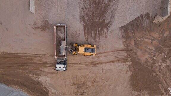 挖掘机将沙子装进大卡车鸟瞰图