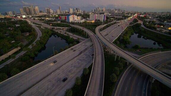 在北迈阿密95号州际公路和I-195号公路之间繁忙的高架交通枢纽日落时分用超宽镜头拍摄的迈阿密市区和设计区远处的景象无人机拍摄的前移镜头
