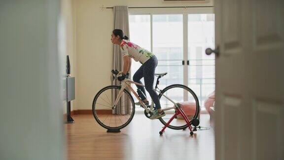 亚洲运动女性在家里锻炼自行车