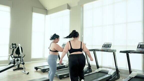 两个超重的亚洲女人决心通过锻炼来减肥的朋友邀请对方在空闲时间在乡村俱乐部健身房的跑步机上跑步生活方式与运动