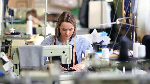 专注的女裁缝工作在生产线上的专业服装裁缝工作室