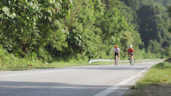 职业自行车手在乌鲁兰加乡村地区骑公路旅行与2名铁人三项运动员骑手在早上